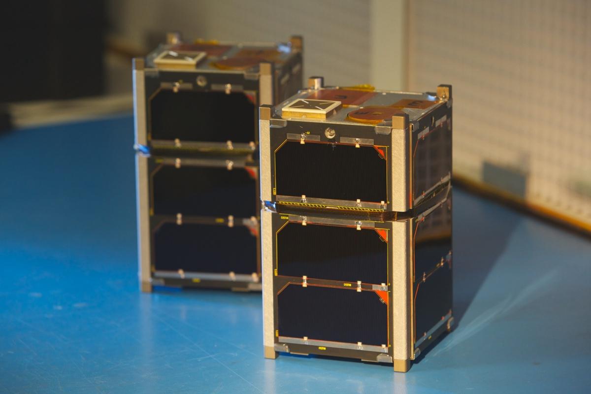 Two small satellites sit on a bench.